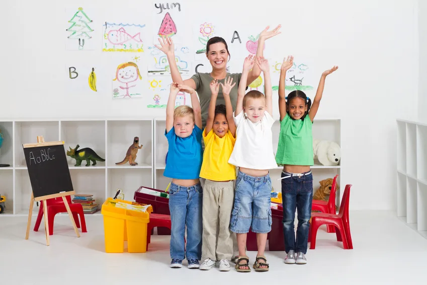 Children and teacher smiling with hands raised in a colorful classroom, celebrating how to create impactful project displays.