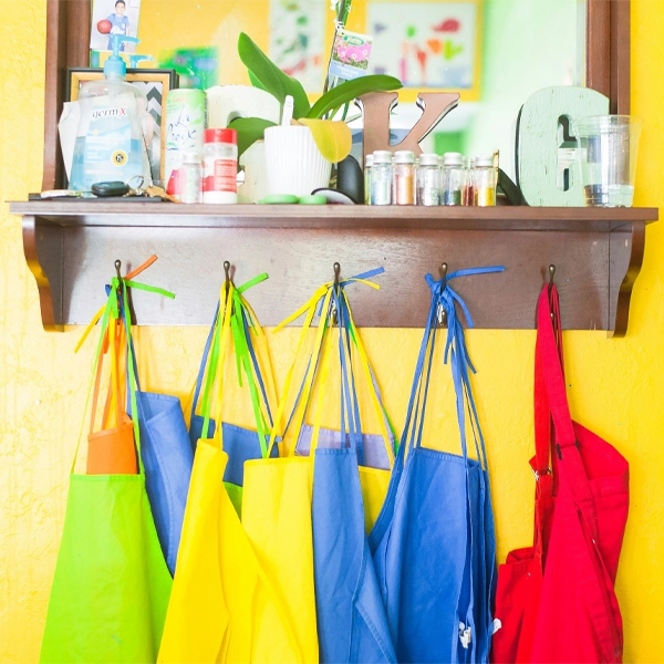 Blog Post 9.27 Colorful aprons hanging under a shelf in a creative classroom setting