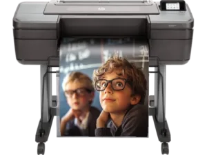 A large-format printer with a poster of two young boys wearing glasses, one focused and the other blurred in the background