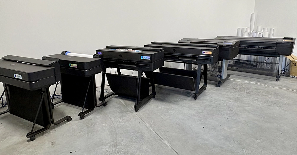 Row of wide-format poster printers staged at the Poster Studio Express warehouse in Mooresville, NC, where print technicians prep systems for schools