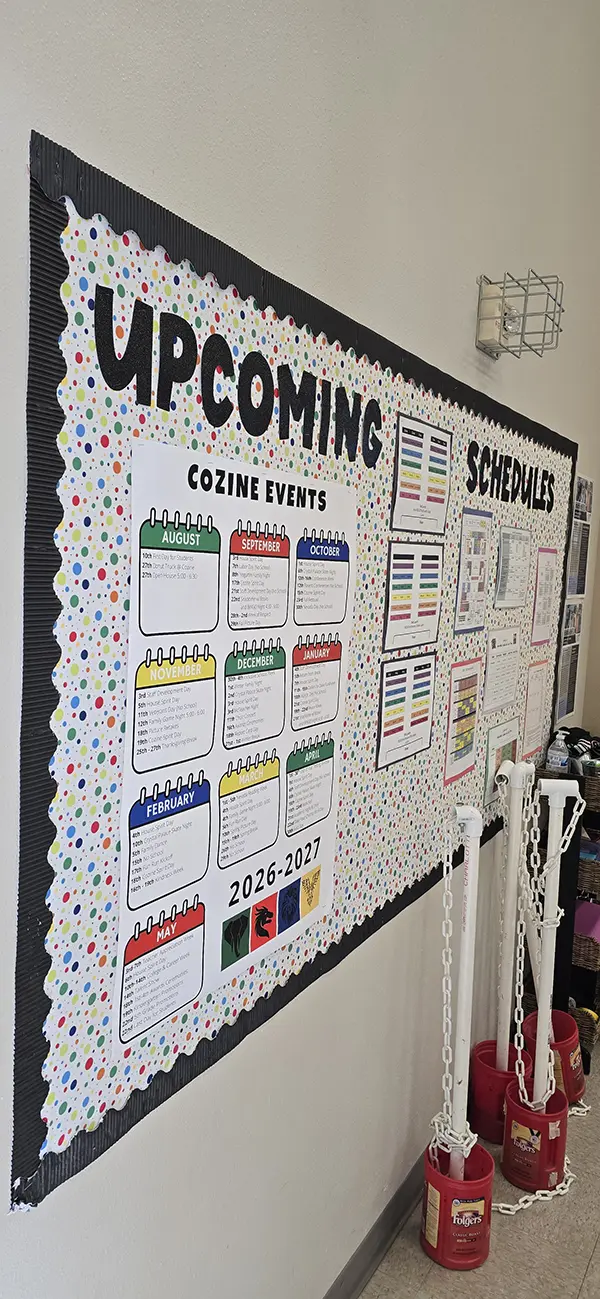 Cozine Events 2026-2027 calendar poster on the Upcoming Schedules bulletin board at Steve and Linda Cozine Elementary School
