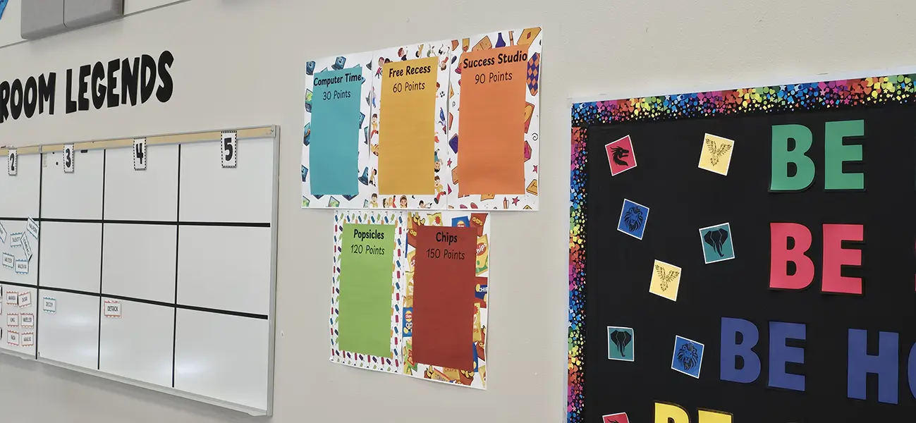 Classroom reward points posters next to a house values bulletin board at Steve and Linda Cozine Elementary School